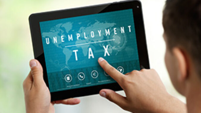 Image of man using a tablet with the words 'unemployment tax' on the screen