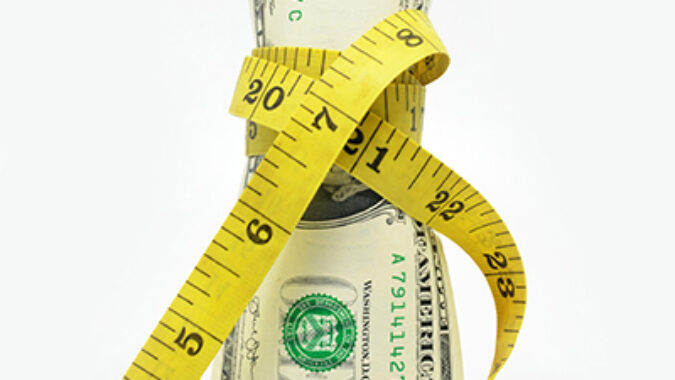 image of dollar bill being squeezed by tape measure